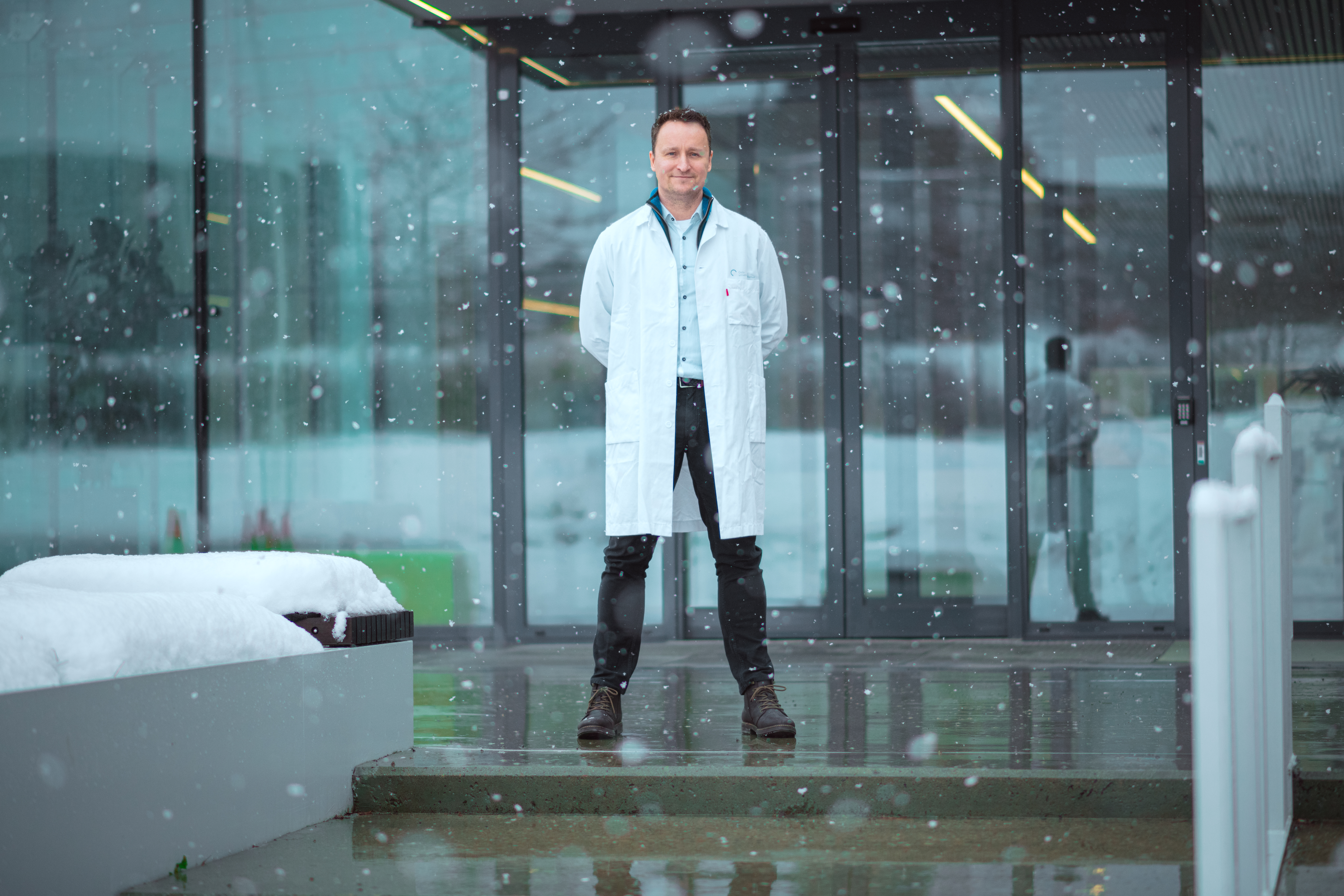 Mannlig forsker står stolt på toppen av en trapp foran et sykehus